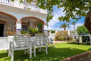 une table et des chaises blanches sur la pelouse d'une maison dans l'établissement Lovely holiday residence with a delicious pool, à Malaga