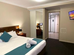 una camera da letto con un letto e asciugamani di City Ville Apartments and Motel a Rockhampton