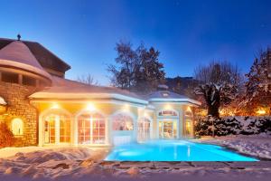 a house with a pool in the snow at night at Romantikhotel Zell am See in Zell am See