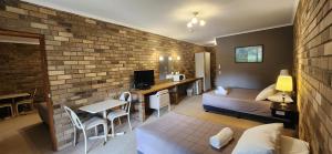 a bedroom with a bed and a brick wall at Magdala Motor Lodge & Lakeside Restaurant in Stawell