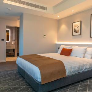 una camera da letto con un grande letto con cuscini bianchi di The Gable Inn a Scone