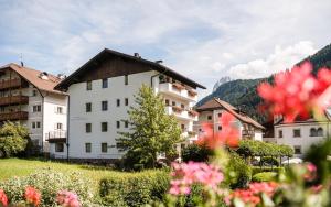 un gruppo di edifici con fiori in primo piano di B&B Villa Angelino a Ortisei