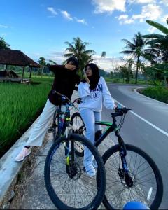 deux femmes debout à côté de leurs vélos sur une route dans l'établissement Florence guest house mataram lombok, à Mataram