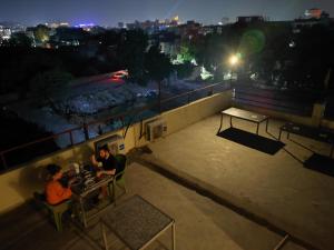 two people sitting at a table on a balcony at night at Sunrise Homestay in Agra