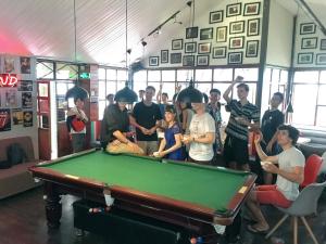 a group of people standing around a pool table at Kunming Upland International Youth Hostel in Kunming