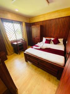 - une chambre avec un grand lit et des oreillers rouges dans l'établissement Mountain Mist Meadows, à Ooty