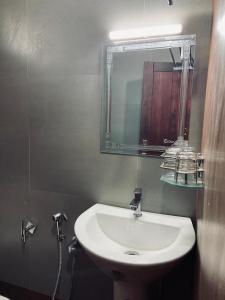 La salle de bains est pourvue d'un lavabo blanc et d'un miroir. dans l'établissement Mountain Mist Meadows, à Ooty
