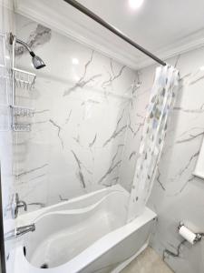 La salle de bains blanche est pourvue d'une baignoire et d'une douche. dans l'établissement Toronto Uptown 1, à Toronto