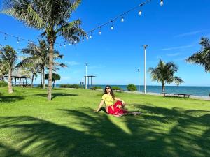 a woman sitting on the grass near the beach at Oceanami Villa Long Hải - Vũng Tàu in Long Hai