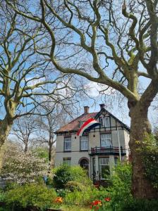 a house with a flag on the top of it at B&B Slapen bij de burgemeester in Sint Pancras