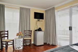 a living room with a television and a table with chairs at Point Village Guest House in Mossel Bay