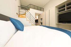a bedroom with a bed with blue pillows and a staircase at Coopstay Yeosu Hotel in Yeosu