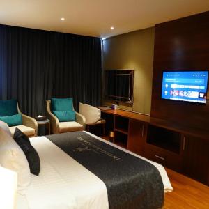 a hotel room with a bed and a flat screen tv at Indigo Heights Hotel & Suites in Lahore