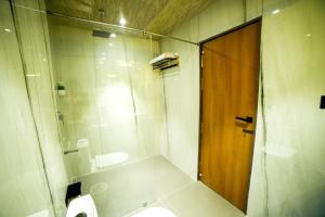 a bathroom with a shower and a toilet and a wooden door at Hotel Surya, Kaiser Palace in Varanasi