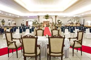 um salão de banquetes com mesas e cadeiras brancas numa sala em Hotel 678 Cawang powered by Cocotel em Jacarta