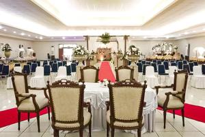 Hotel 678 Cawang powered by Cocotel في جاكرتا: قاعة احتفالات بطاولات بيضاء وكراسي في غرفة