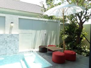 eine Terrasse mit einem Tisch, roten Stühlen und einem Sonnenschirm in der Unterkunft Paul Pool Villa Pattaya in Bang Sare