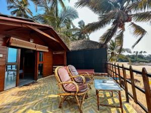 two chairs and a table on a porch of a house at O3 Beach Resort in Palolem