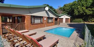 a house with a swimming pool and two deck chairs at Kerynmere, 114 Nkwazi Drive, Zinkwazi Beach in Zinkwazi Beach