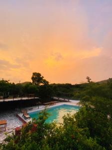 uma piscina com um pôr-do-sol ao fundo em The Mudcasa villa em Udaipur