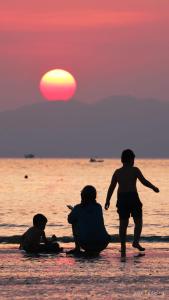 drie mensen op het strand kijkend naar de zonsondergang bij Coto Center Homestay in Dao Co To