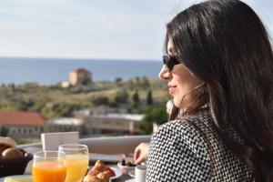 una mujer sentada en una mesa con comida y bebidas en Sands Hotel en Jbeil
