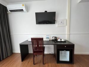 a desk with a chair and a television on a wall at บ้านสวนสมบูรณ์ in Sangkhla Buri