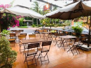 un patio al aire libre con mesas, sillas y sombrillas en Chào Hotel Mũi Né en Mui Ne