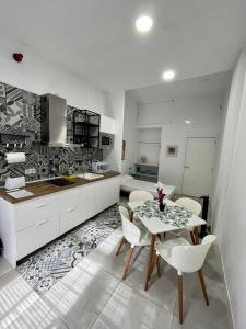 uma cozinha branca com uma mesa e cadeiras brancas em El Mosaico Apartment em Valência