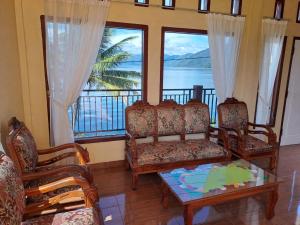 a living room with chairs and a table and windows at OYO 93241 Hotel Puri Azzura Danau Ranau in Jepara