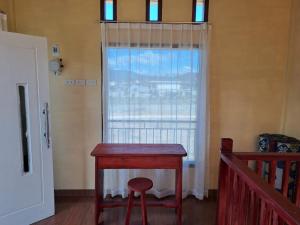 a red table with a stool in front of a window at OYO 93241 Hotel Puri Azzura Danau Ranau in Jepara