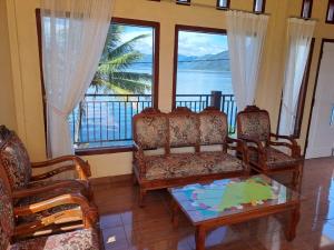 a living room with two chairs and a table and windows at OYO 93241 Hotel Puri Azzura Danau Ranau in Jepara