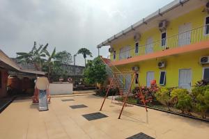 un parque infantil en el patio de un edificio en OYO 93252 Garuda Bandara Guesthouse, en Palembang