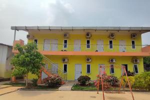 a yellow building with white doors and a balcony at OYO 93252 Garuda Bandara Guesthouse in Palembang