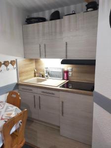 a kitchen with wooden cabinets and a sink at Appartement Manigod/La clusaz in Manigod