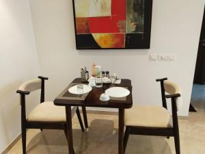 a dining room table with two chairs and a painting at Sapphire Asta- Regent Hills in Mumbai