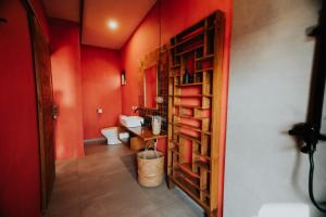 baño con paredes rojas y estantería de madera. en Disini Lombok ECO Sky House, Selong Belanak, en Selong Belanak