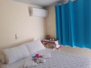 um quarto com uma cama branca e uma cortina azul em Aconchego da Vovó em Araruama