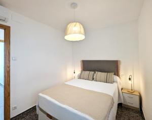 a white bedroom with a bed and a lamp at La posada de Calixto in Valdepeñas