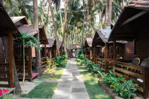 a walkway through a resort with palm trees at O3 Beach Resort in Palolem