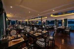 een restaurant met tafels en stoelen en uitzicht op de oceaan bij Genesis Luxury Regal Cruises in Ha Long