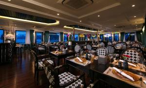 Genesis Luxury Regal Cruises في ها لونغ: غرفة طعام مع طاولات وكراسي في مطعم