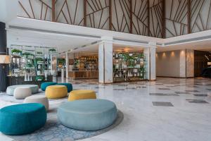 um átrio com mesas e cadeiras azuis e amarelas em Holiday Inn & Suites Rayong City Centre, an IHG Hotel em Rayong