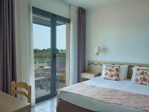 a bedroom with a bed and a balcony with a table at Atlantica Mikri Poli Rhodes in Kolimbia