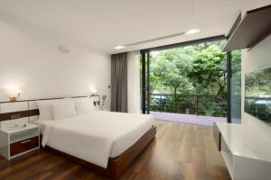 a bedroom with a white bed and a large window at Flamingo Dai Lai Resort in Ngọc Quang