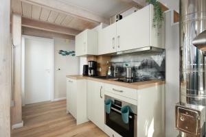 een keuken met witte kasten en een fornuis bij Haus Windjammer Windjammer Danmark in Laboe