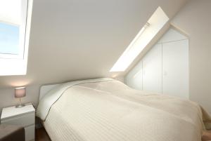 een witte slaapkamer met een bed en een dakraam bij Haus Windjammer Windjammer Danmark in Laboe