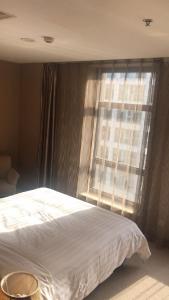 um quarto com uma cama branca e uma janela em Dalian Asia Pacific Service Apartment (Former Somerset Harbour Court Dalian) em Dalian