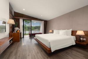 a bedroom with a large white bed and a large window at Flamingo Dai Lai Resort in Ngọc Quang