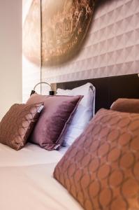 a bed with purple and white pillows on it at Golden Tulip Leiden Centre in Leiden
